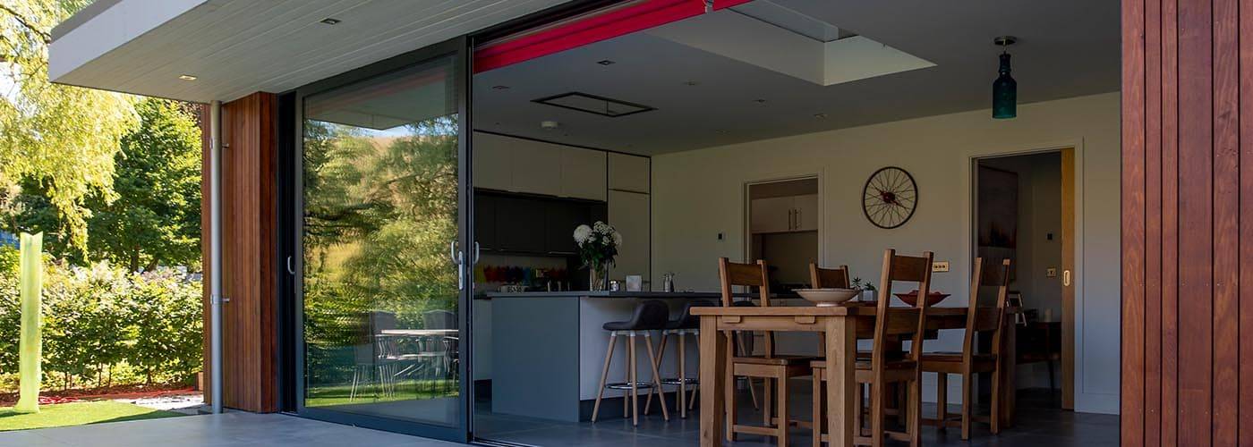 large aluminium framed sliding doors leading from kitchen to patio area of modern home
